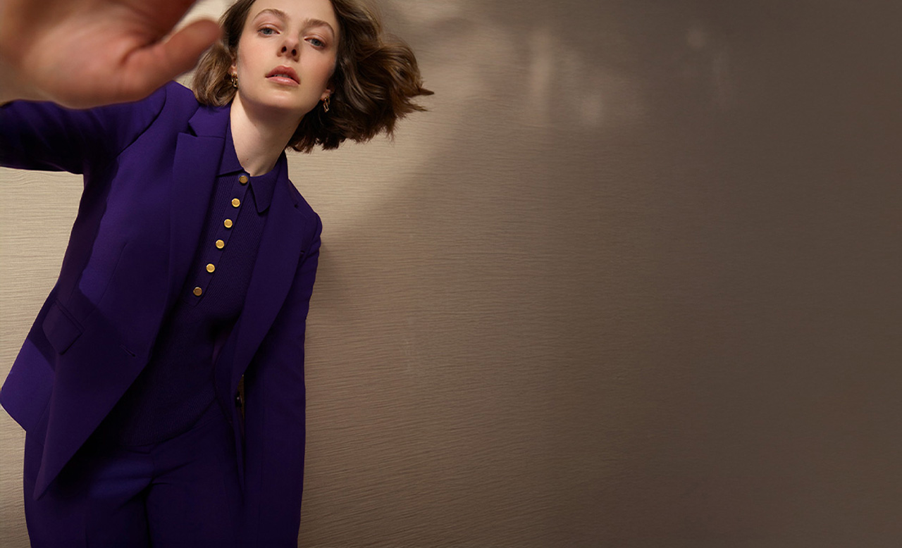 A woman wearing a purple tailored suit.