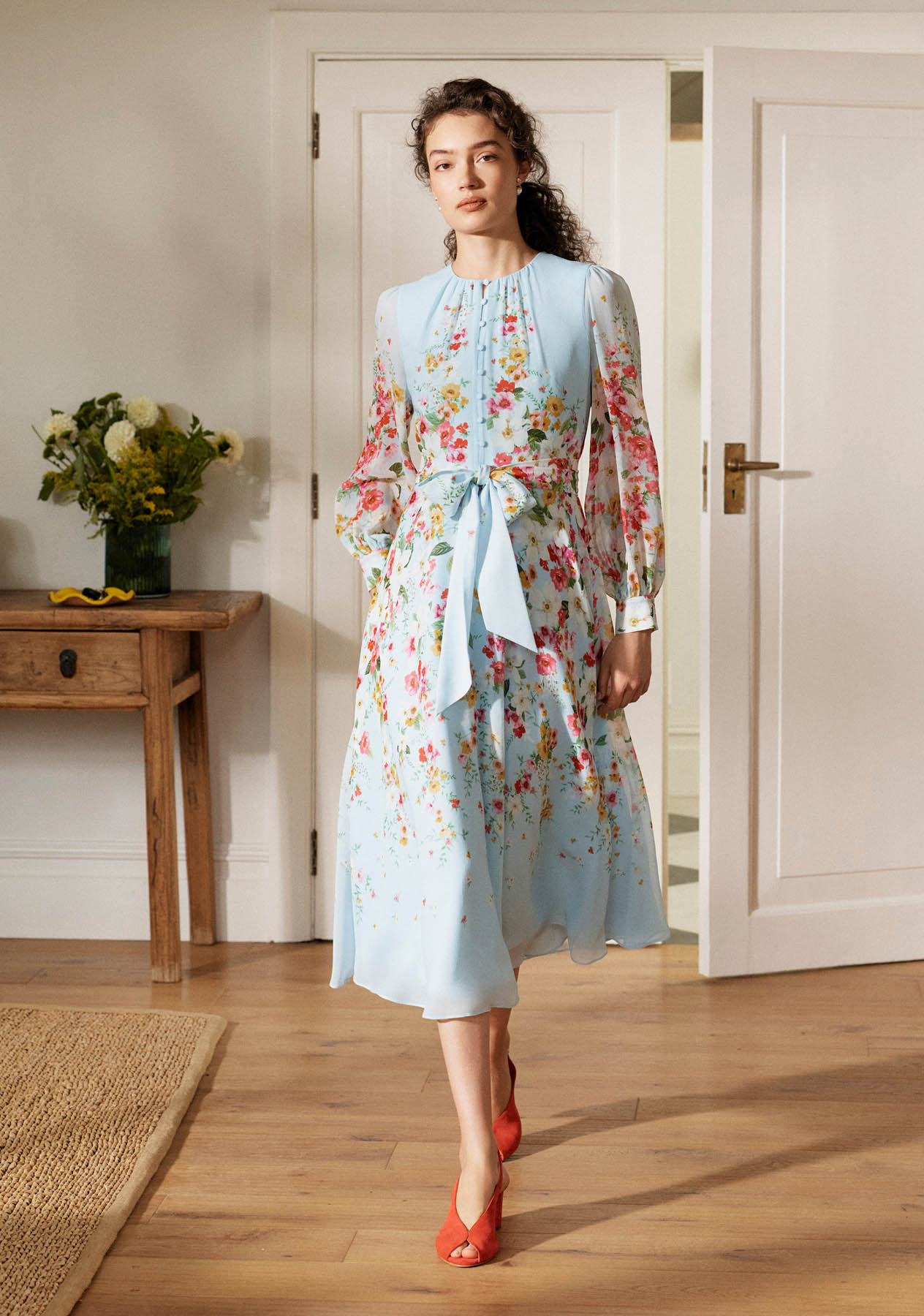 A woman wearing a floral print silk dress.