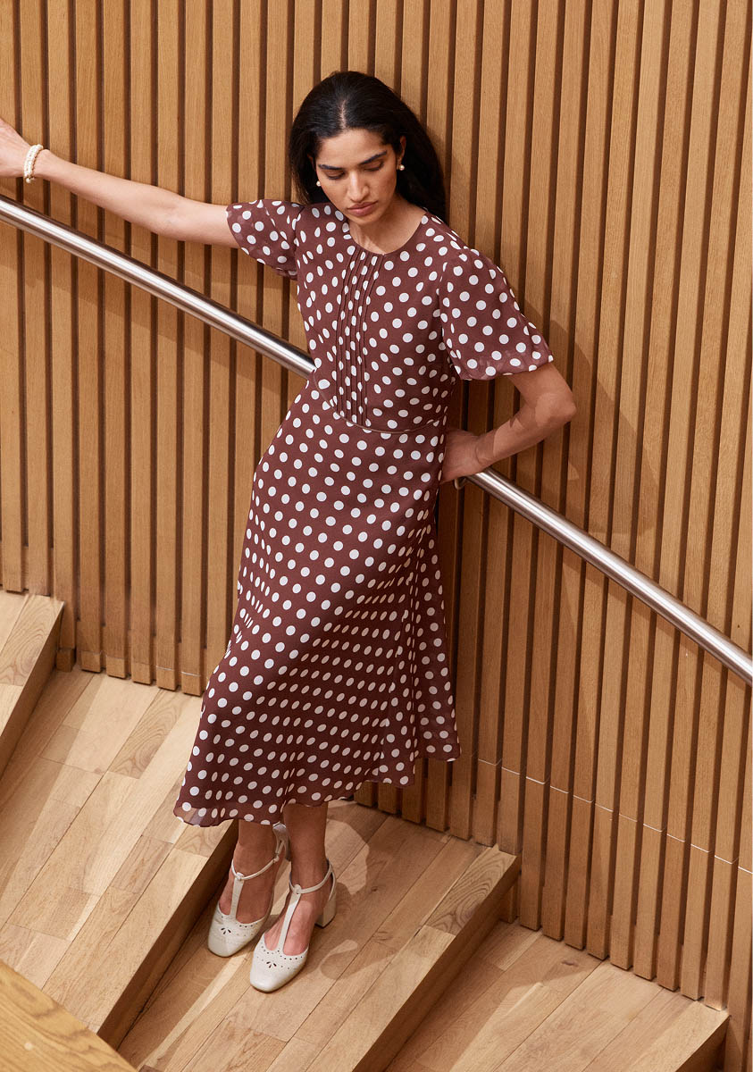 A woman wearing a brown polka dot dress.