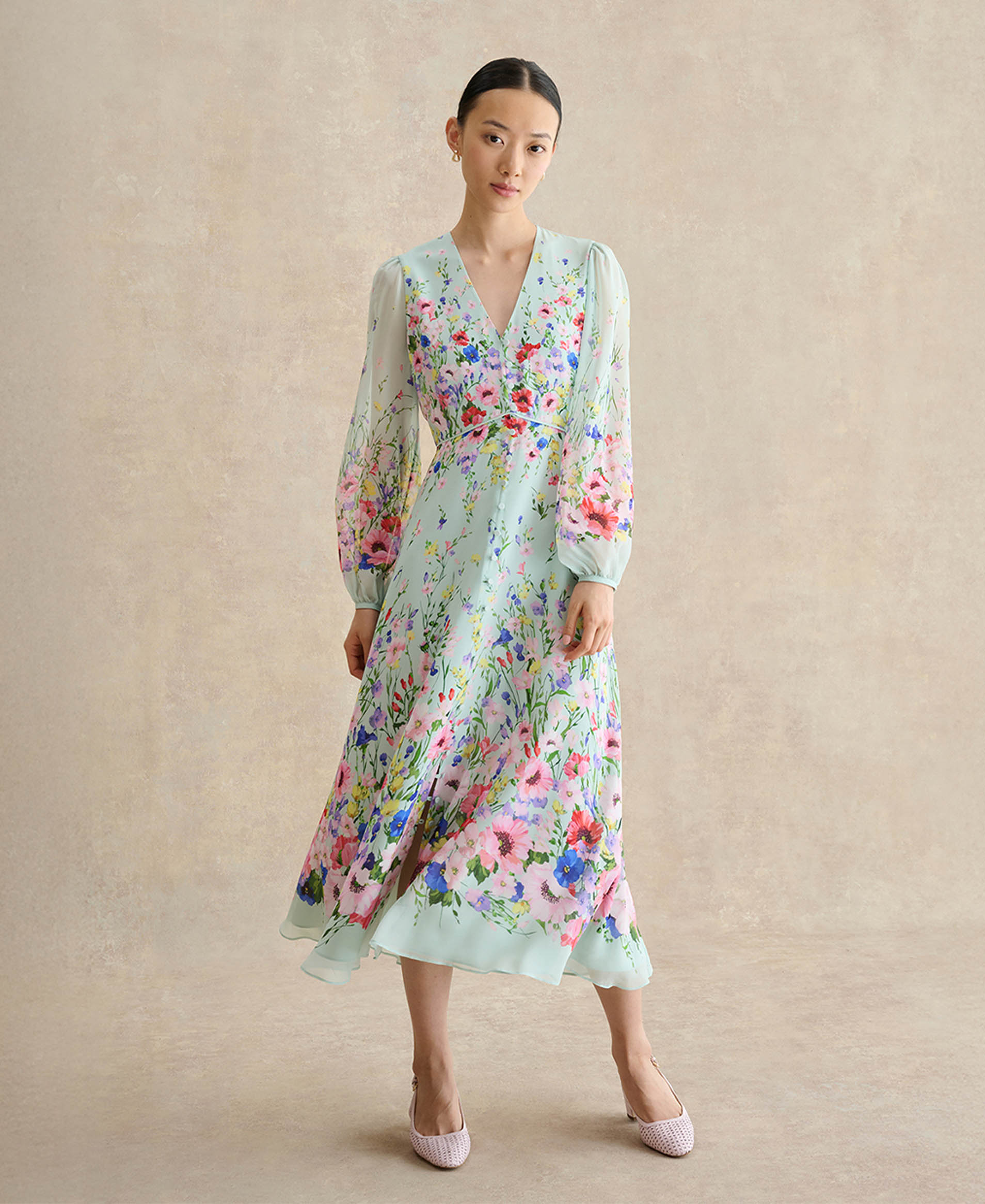 A woman wearing a sage green wedding guest dress.