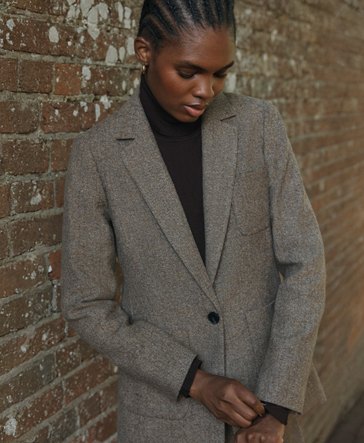 A woman wearing a woven, tweed smart jacket.