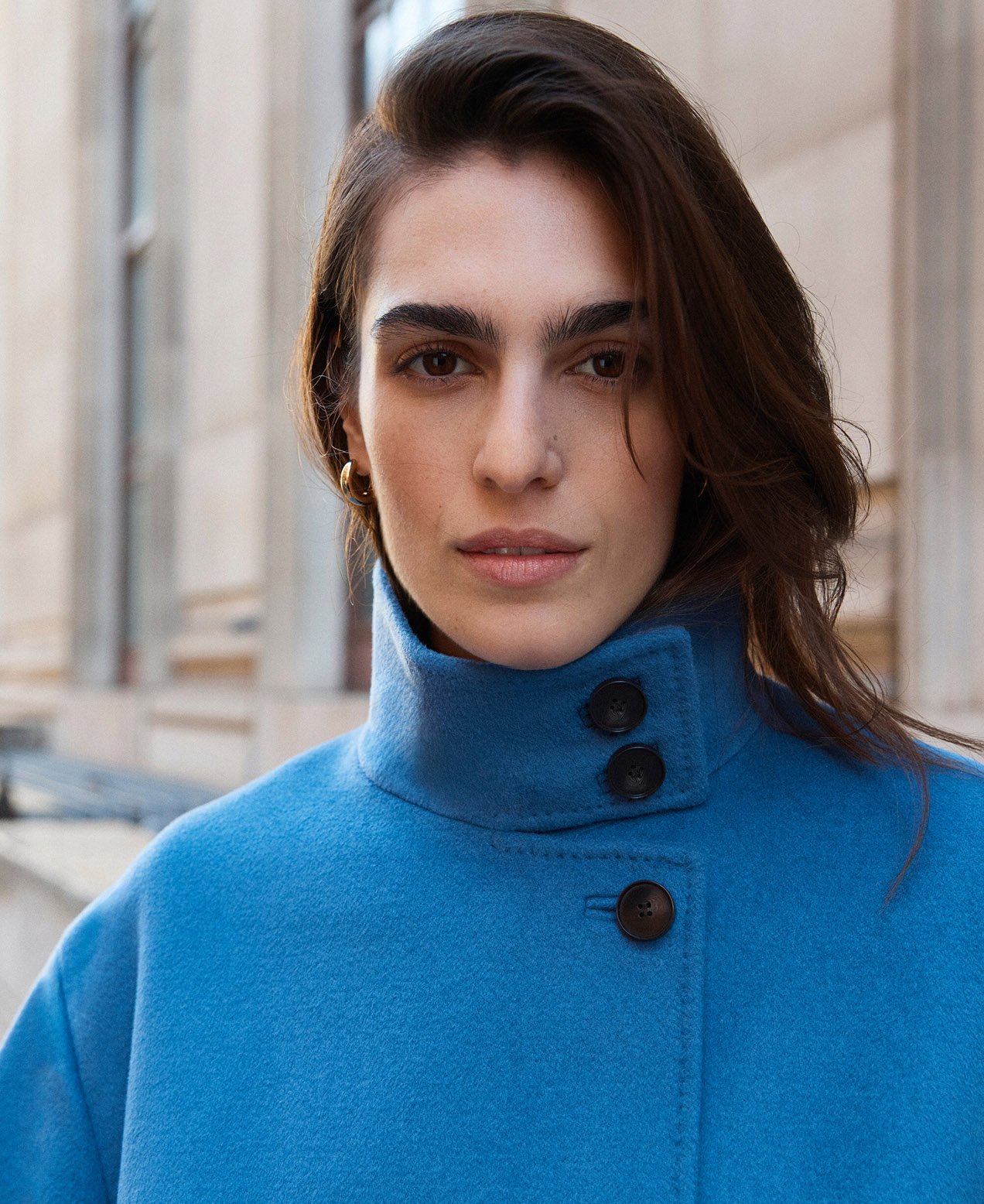 A woman wearing a cerulean blue, wool blend coat.