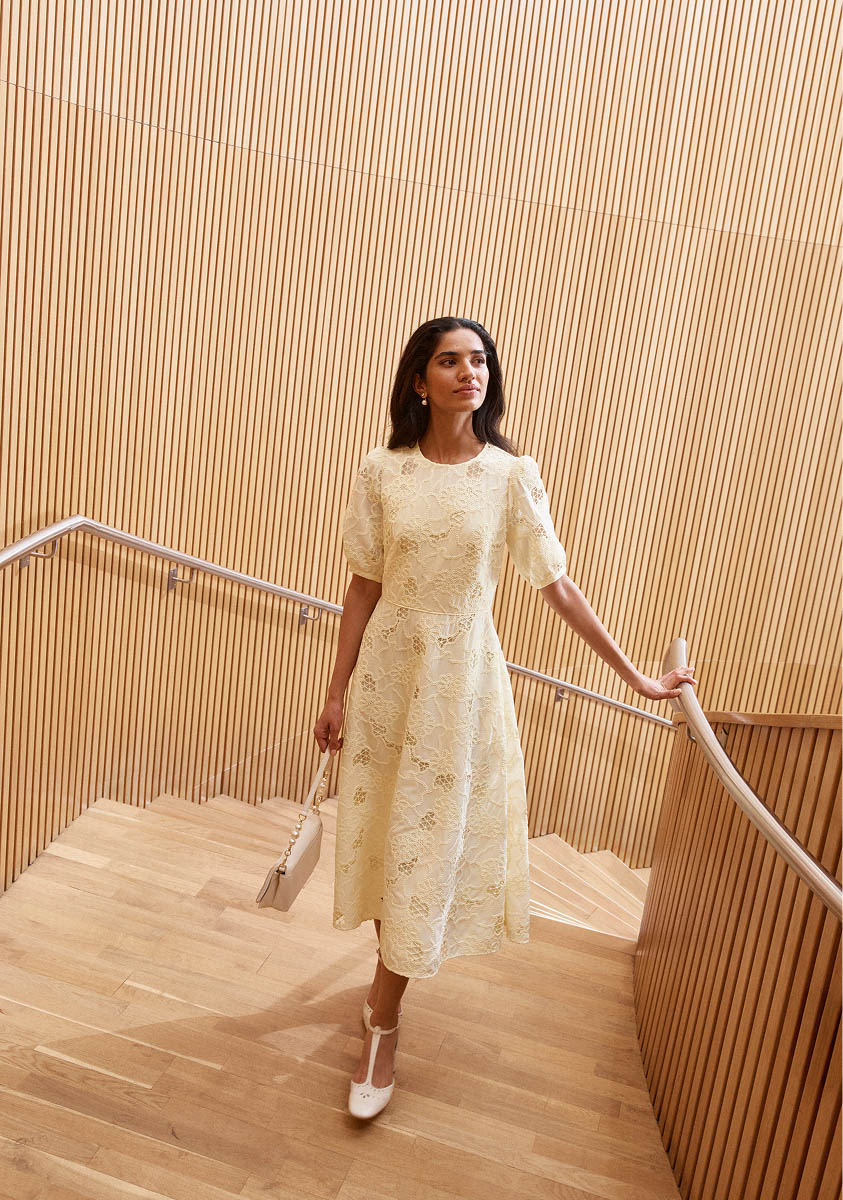 A woman wearing a butter yellow midi dress.