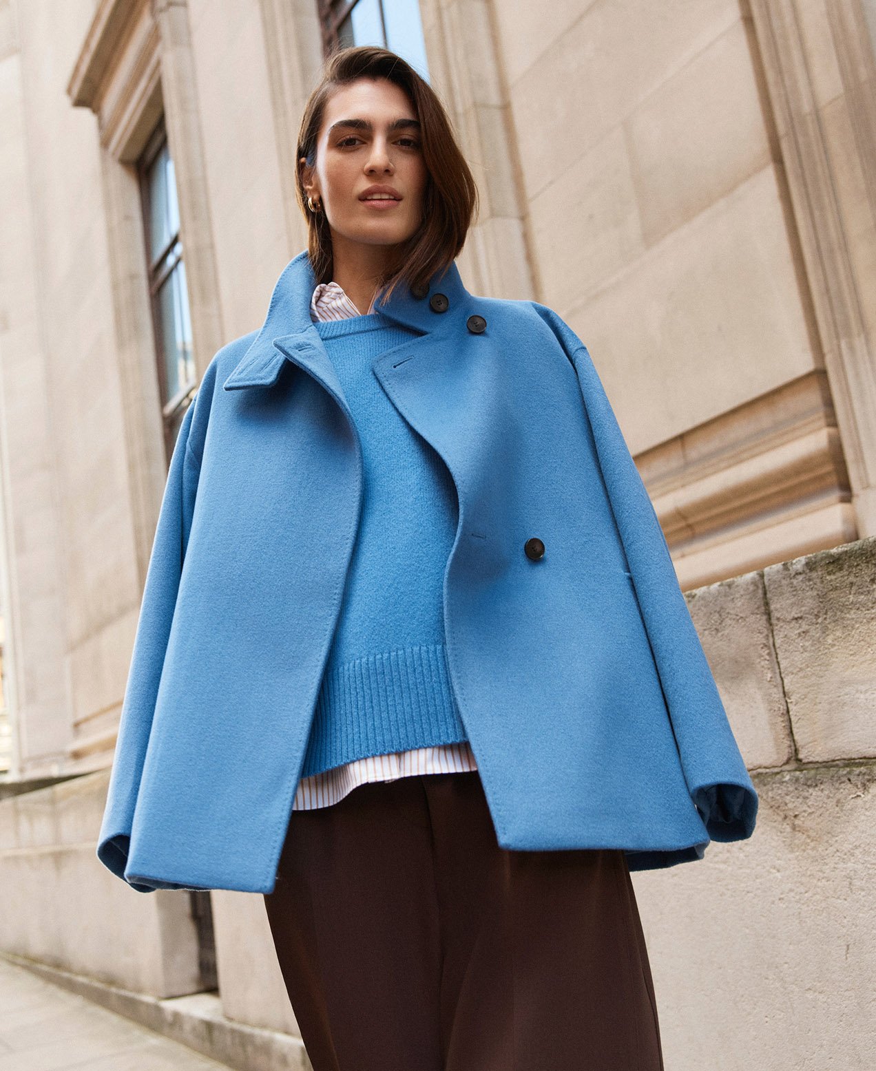 A woman wearing a cerulean blue, wool blend coat.