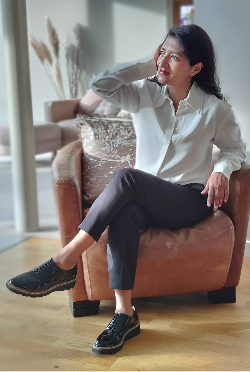 Photographed at home, fashion blogger Monika Mandal wears Hobbs Eva silk shirt, petite Quin navy trousers and Bloomsbury black patent lace-up shoes.