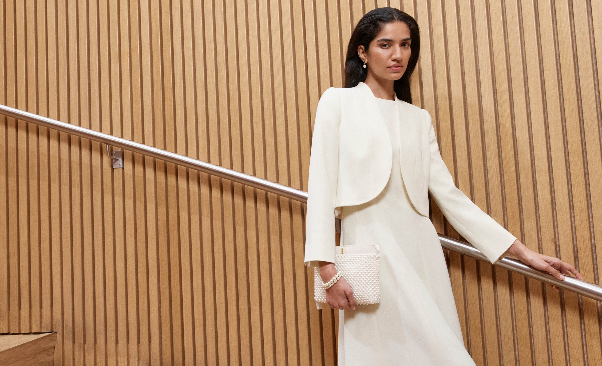 A woman wearing a butter yellow occasion dress and co-ordinating jacket.
