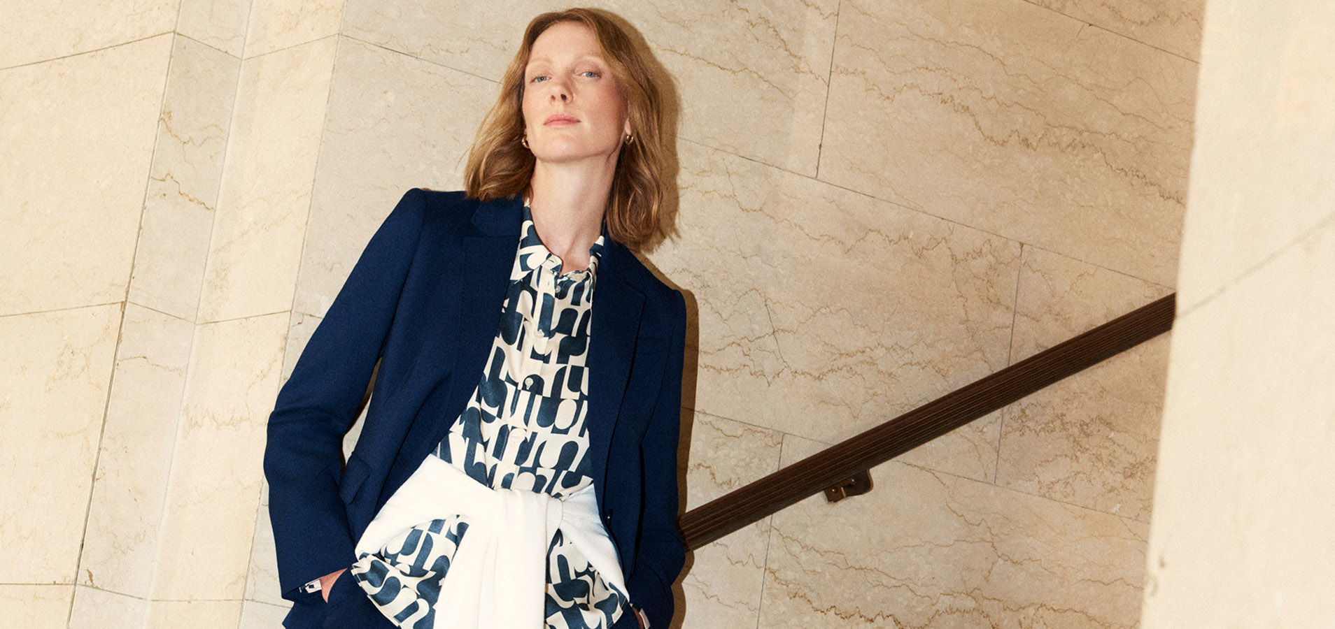 A model wearing a navy suit and print blouse.